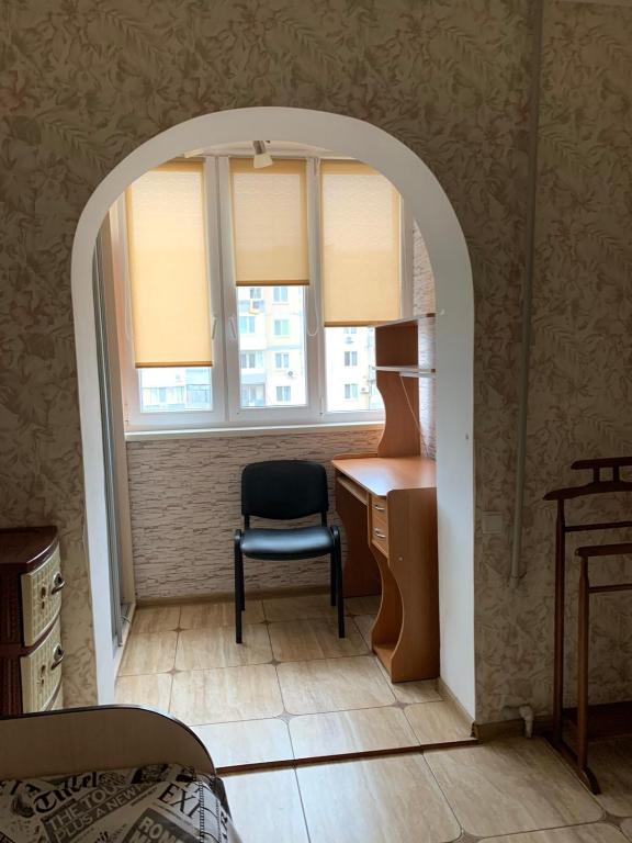 敖德萨131 проспект Добровольского Хорошая 3-х комнатная квартира в Одессе的客房设有书桌、椅子和窗户。