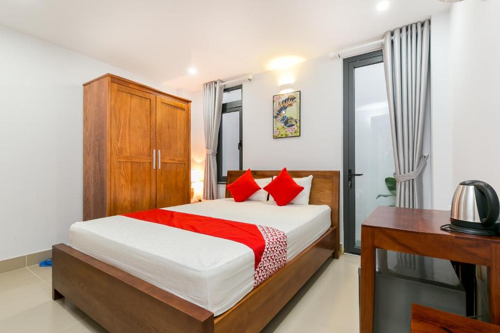 胡志明市Super OYO 520 Friendly Homestay的一间卧室配有一张带红色枕头的床和一张书桌
