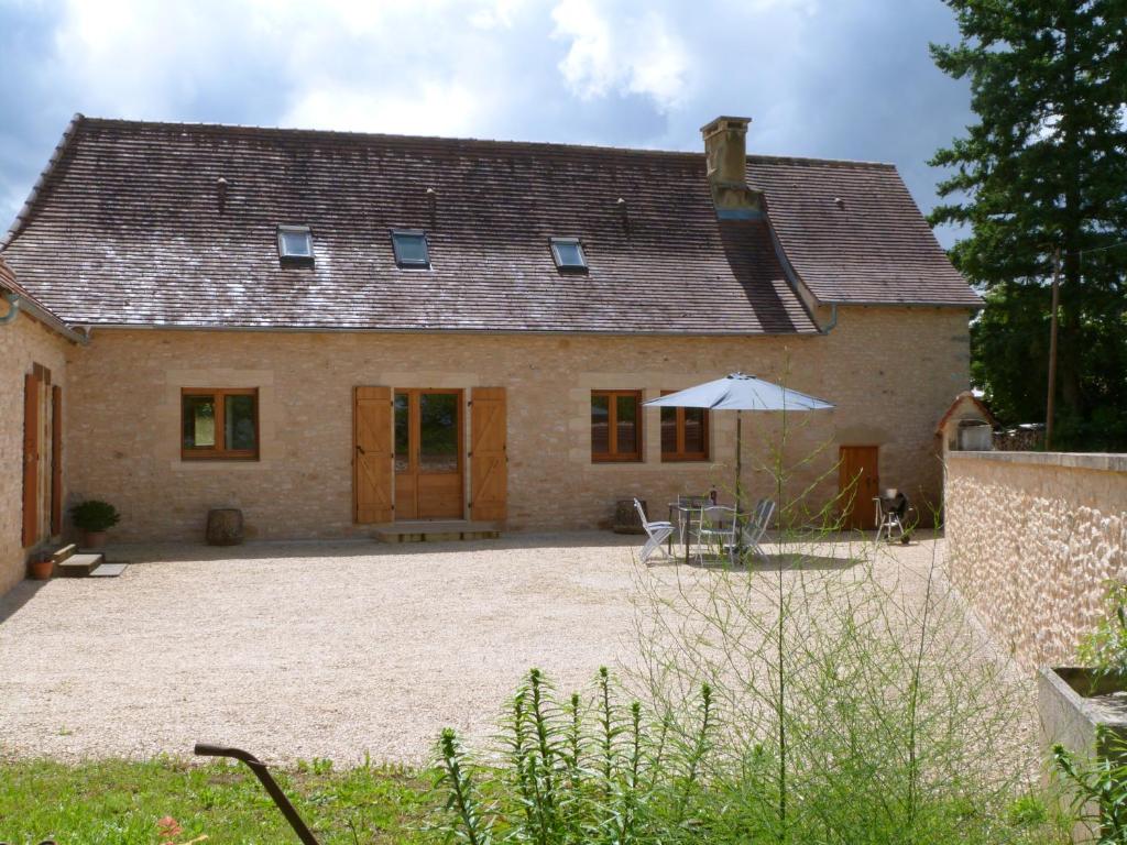 FleuracMaison Périgord Noir près de Lascaux, Montignac, Sarlat, Périgueux的房屋前设有天井和遮阳伞