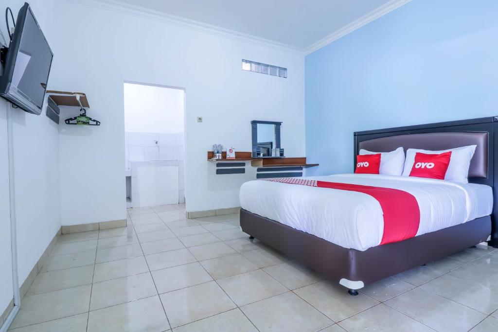 库塔SUPER OYO 1755 De'balcon Accomodation Near Ngurah Rai Airport的一间卧室配有一张带红色枕头的床和一台电视。