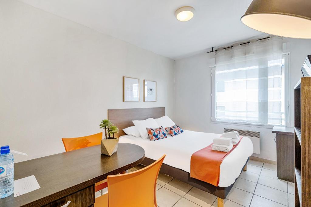 托农莱班Appart'City Classic Thonon Les Bains的卧室配有一张床和一张桌子及椅子