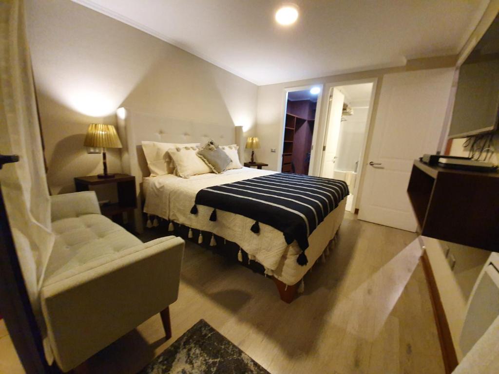 圣地亚哥Mojens Suites Santiago的一间卧室配有一张床、一张沙发和一把椅子