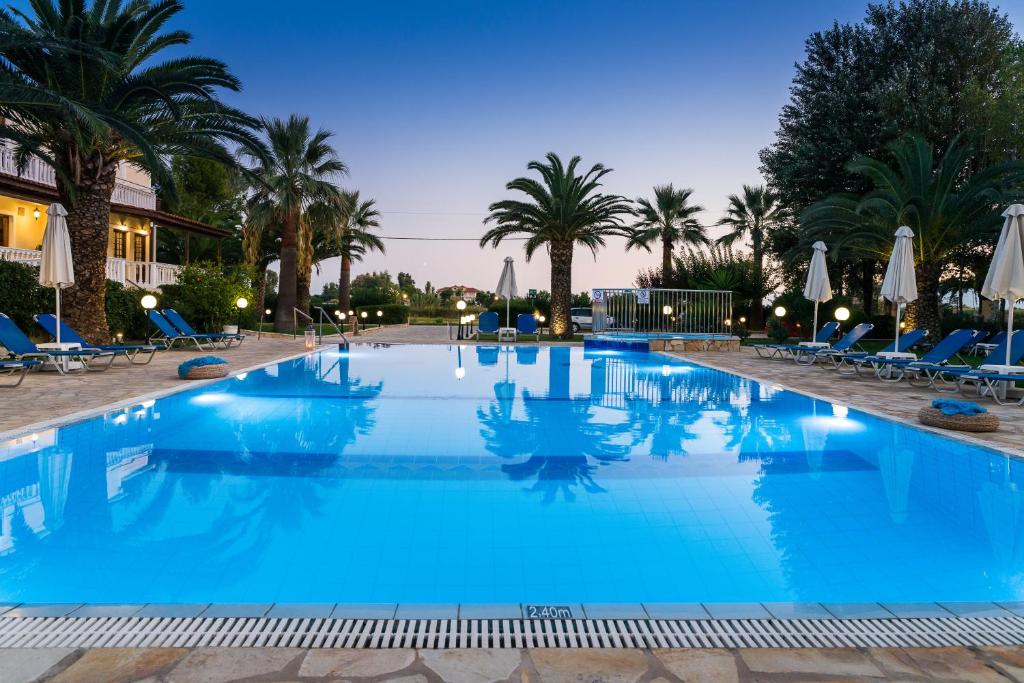 卡拉马孔Kalidonio Studios的一座拥有蓝色水和棕榈树的大型游泳池