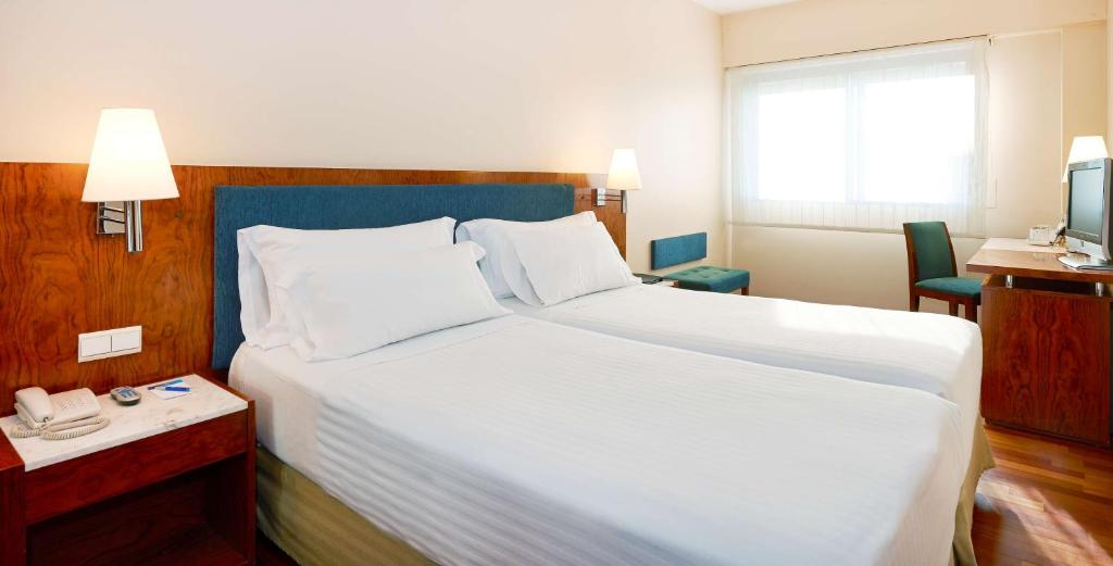 巴塞罗那巴塞罗那昂特扎NH酒店的酒店客房设有一张白色大床和电话。