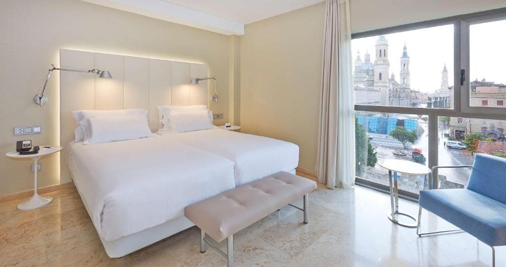 萨拉戈萨NH萨拉戈萨城市酒店的卧室设有白色的床和大窗户