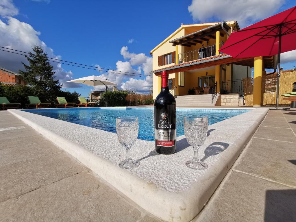 罗波里卡House ANA - Loborika, Pula, 4 bedrooms的游泳池旁的一瓶葡萄酒和两杯酒