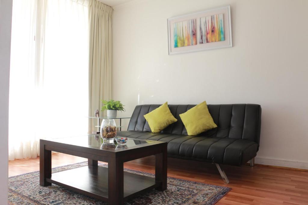 圣地亚哥Austral Rentahome Nueva Providencia的客厅配有黑色沙发和咖啡桌