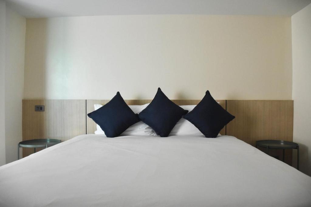 纳通市Stay Inn Nathon Samui的一张白色的床,上面有蓝色枕头