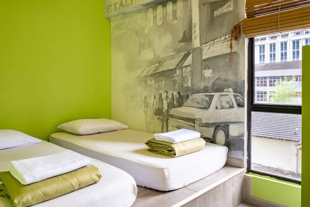 吉隆坡吉隆坡POD背包客咖啡馆旅舍的绿色客房内的两张床,墙上挂着一幅画