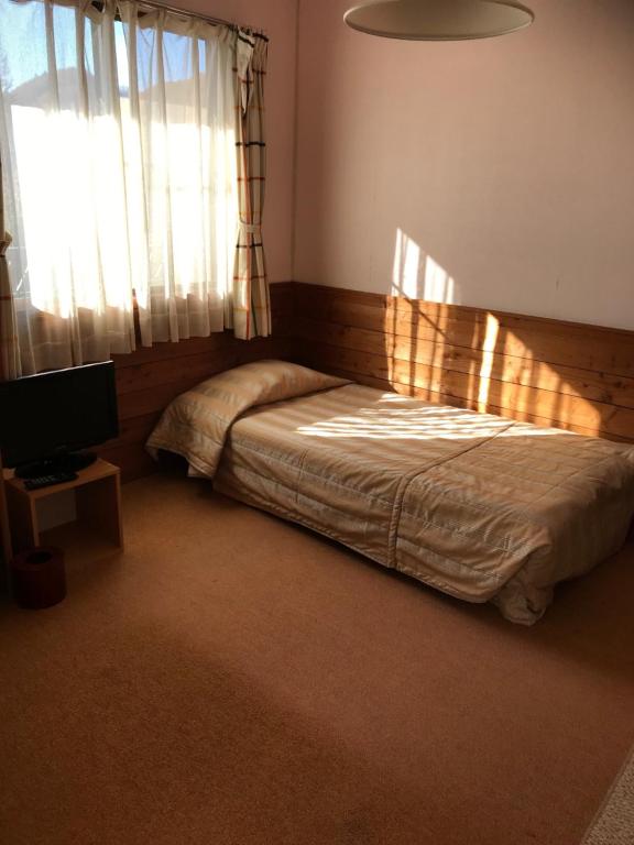 轻井泽尼米旅馆的一间卧室配有一张床、一台电视和一个窗口