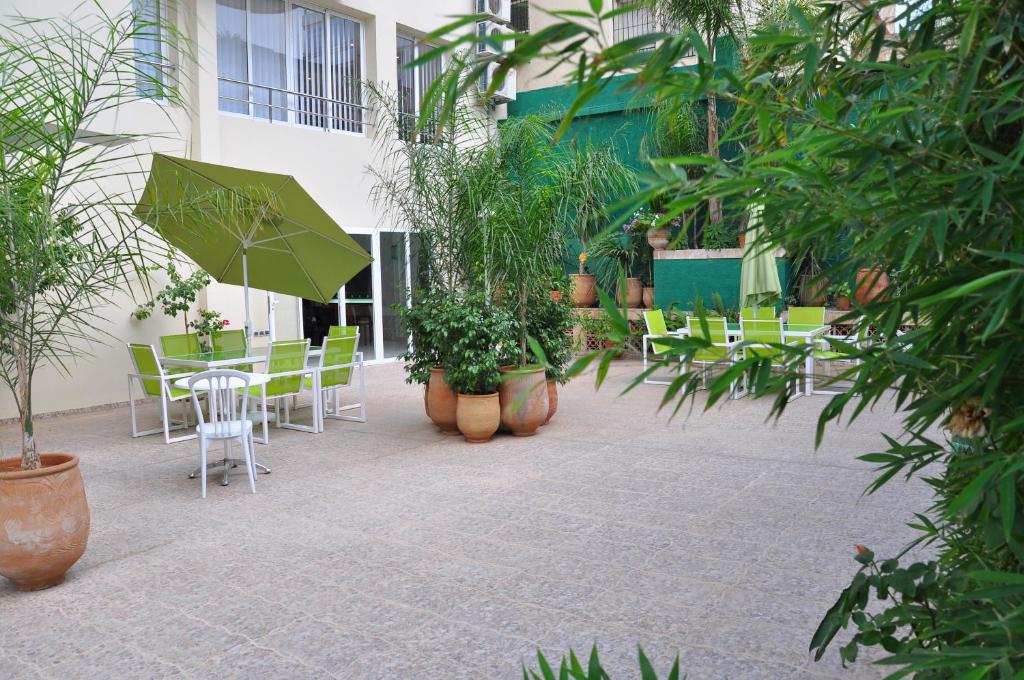 非斯阿克罗斯酒店及Spa的庭院配有椅子和桌子及遮阳伞
