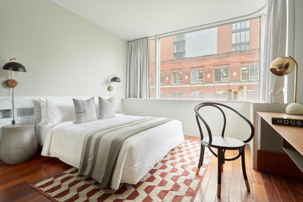 多伦多Sonder The Slate的卧室配有床、椅子和窗户。