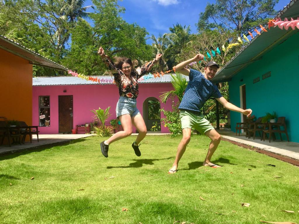 富国Lana Land Homestay Phu Quoc的两个人在房子前面的草地上跳