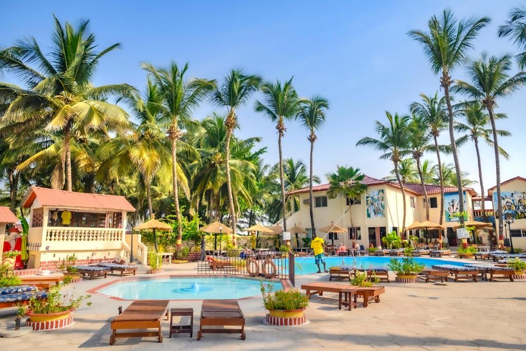 科图棕榈滩酒店的一个带游泳池和桌子以及棕榈树的度假村