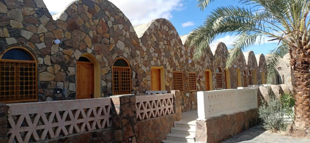 BawatiSafari Camp Bahariya Oasis的一座石头建筑,设有围栏和棕榈树