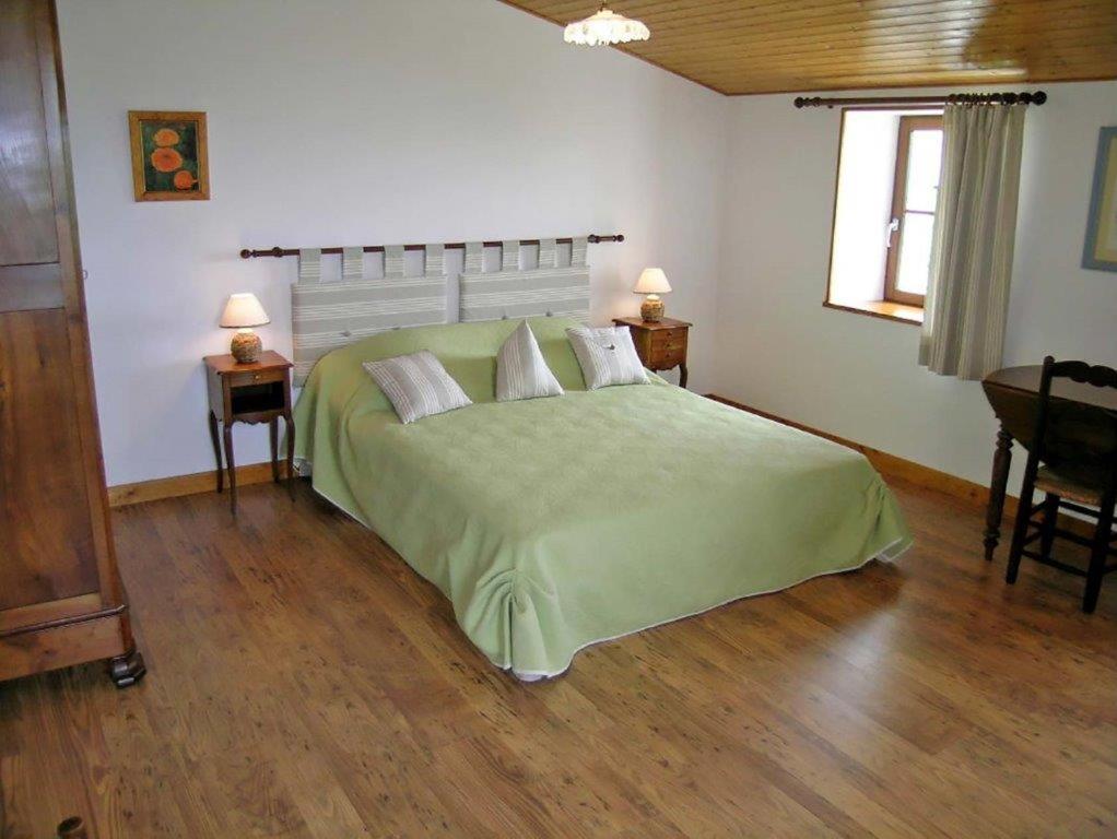 Saint-PorchaireChambres d'Hôtes Domaine Le Fragnaud的一间卧室配有一张带两张桌子的大型绿色床
