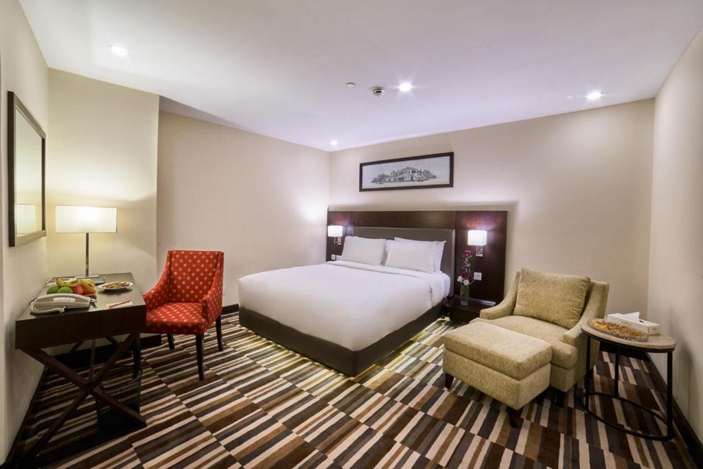 拉合尔Avari Xpress Gulberg的酒店客房,配有一张床、一张桌子和椅子