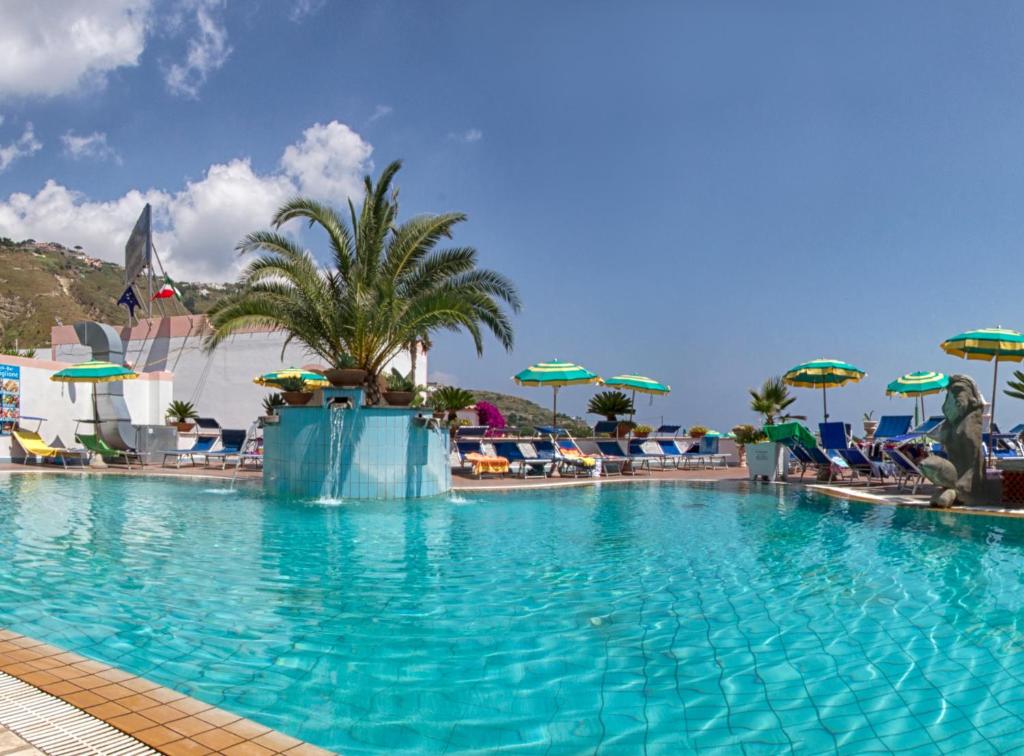 伊斯基亚卡斯蒂廖内酒店的一个带椅子和遮阳伞的大型游泳池