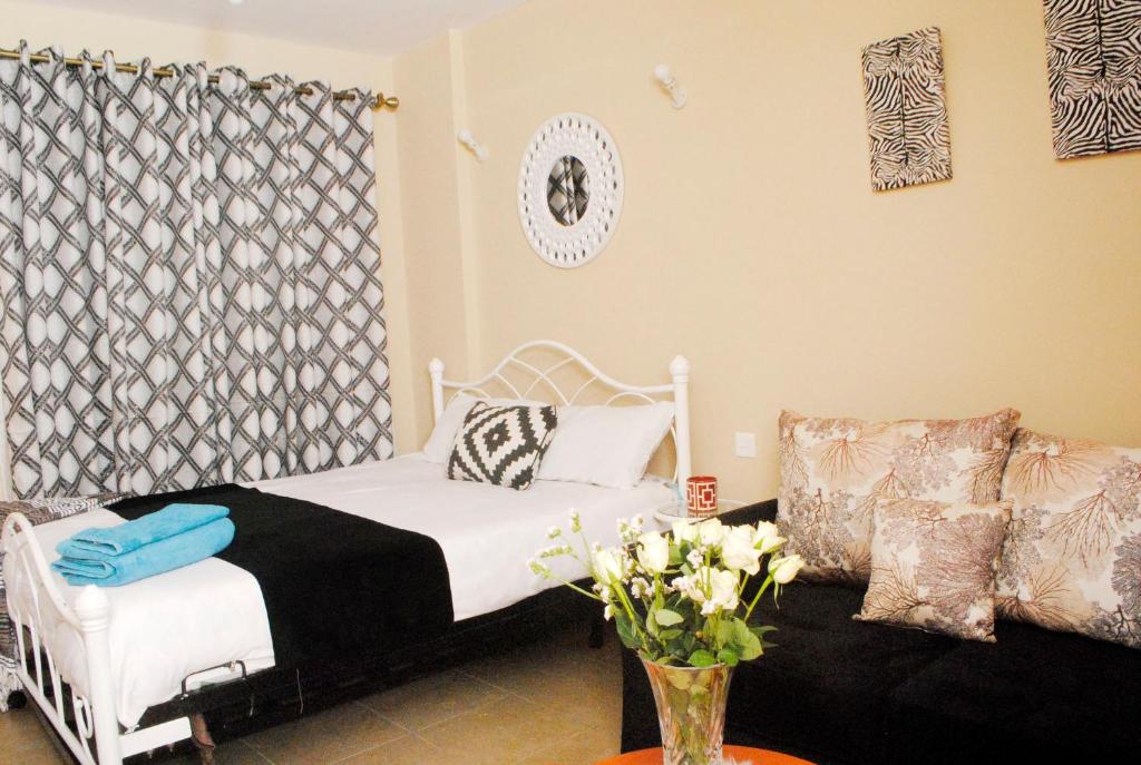 内罗毕WEST SUITES SHERRY HOMES的卧室配有白色的床和沙发