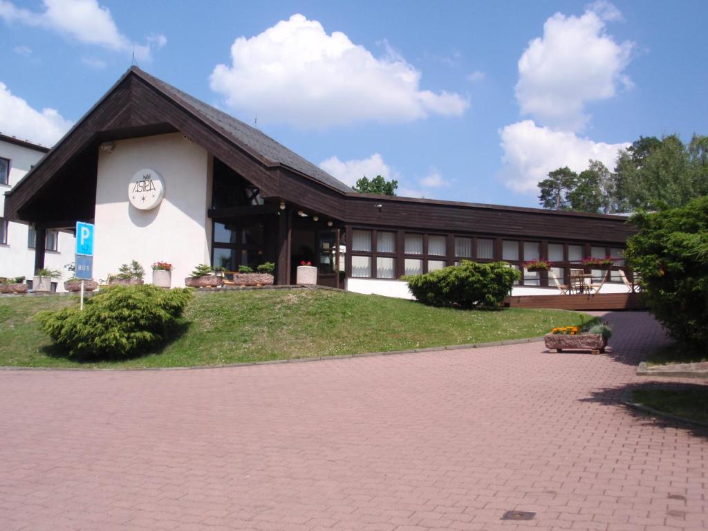 图赫洛维采阿斯特拉酒店的一座有黑色屋顶和砖瓦车道的建筑