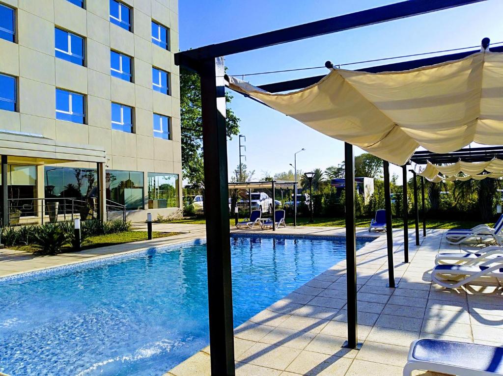 Villa ÁngelaPlatinum Hotel Casino的一座带天蓬和椅子的游泳池位于大楼旁