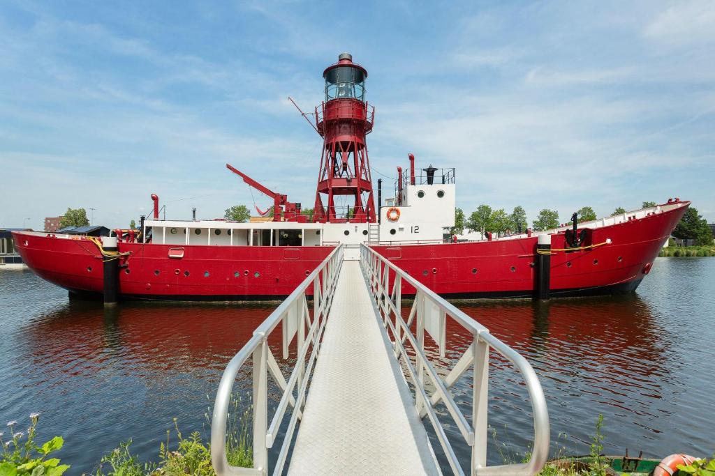 阿姆斯特丹Lightship Amsterdam的灯塔旁边的水中一艘红船