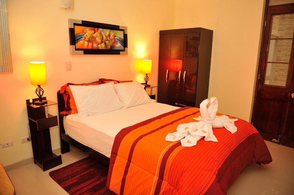 阿雷基帕太阳坦博旅馆的一间卧室配有一张带橙色和白色毯子的床
