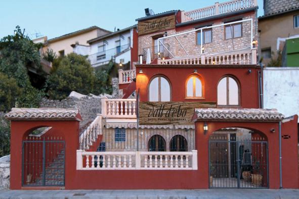 Vall de Ebo琳芬山沟乡村酒店的一座红色的建筑,旁边设有阳台