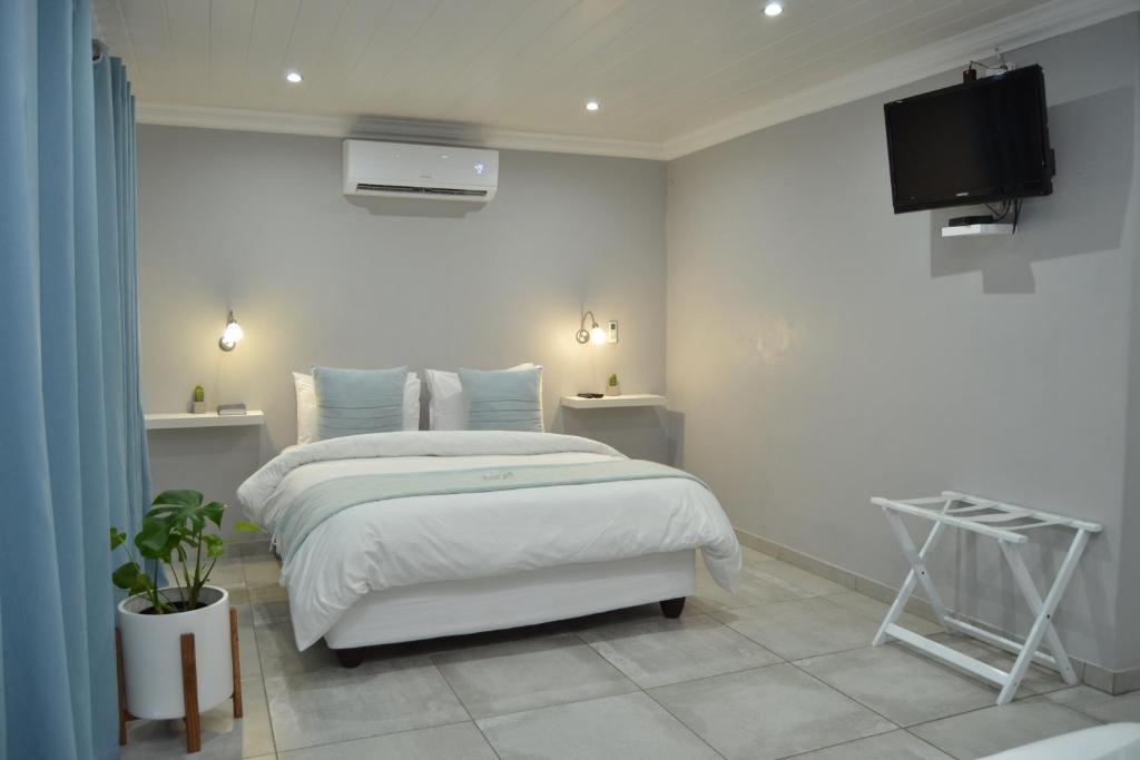 布隆方丹African Sands Guesthouse LOAD SHEDDING FREE的一间白色卧室,配有床和电视