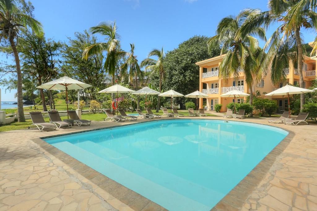Rodrigues Island库库提尔斯酒店 - 罗德里格斯的一个带椅子和遮阳伞的大型游泳池