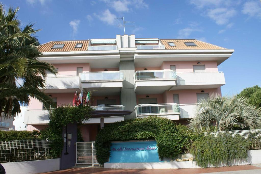 圣贝内代托-德尔特龙托Appartamento Mediterraneo的一座粉红色的建筑,前面有一棵棕榈树
