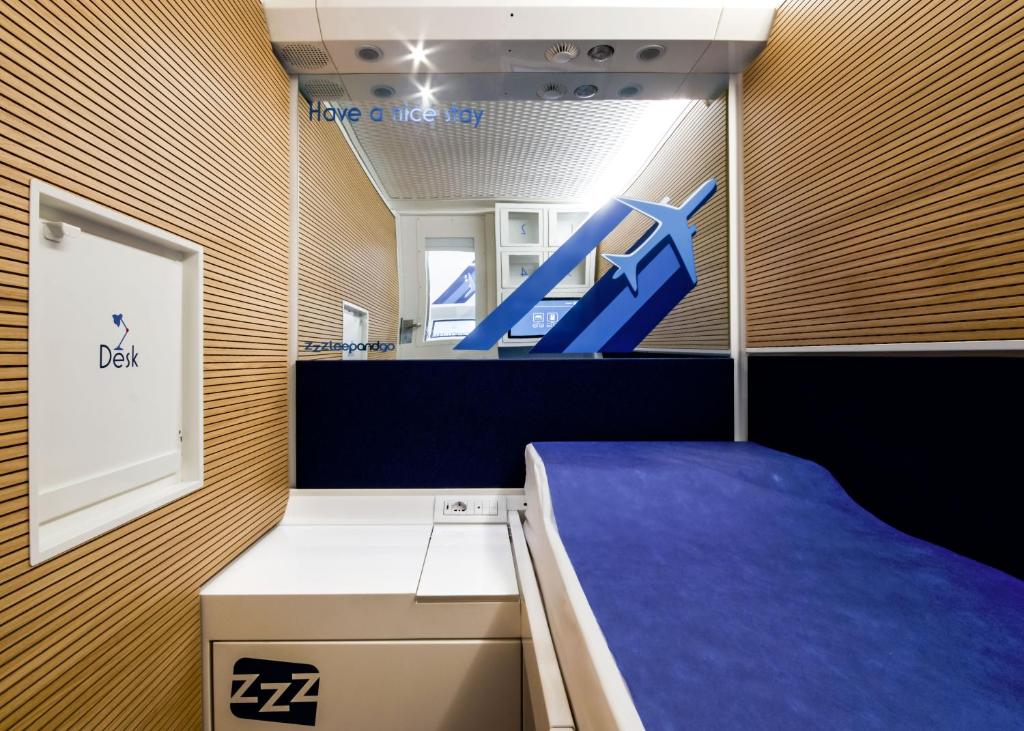 泰塞拉Resting Pods - ZzzleepandGo VCE Venice Airport的配有床和蓝椅的房间