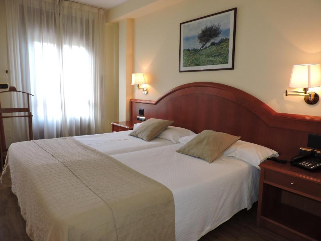 巴利亚多利德伊尔诺加尔酒店的一间卧室配有一张带白色床单的大床