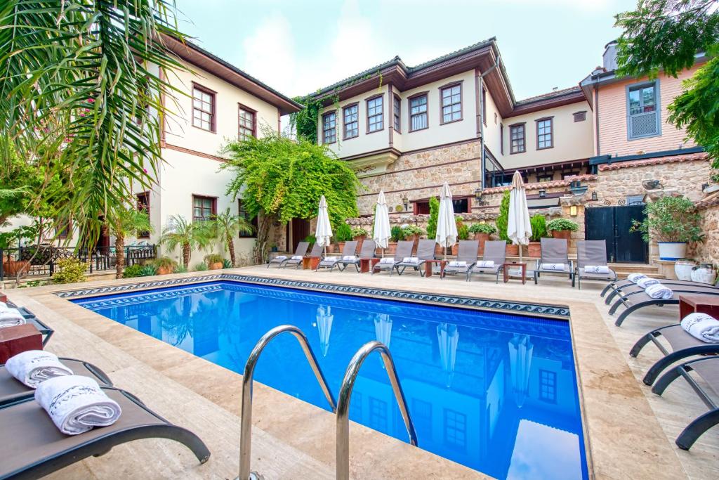 安塔利亚图瓦纳酒店的房屋旁的游泳池配有椅子和遮阳伞