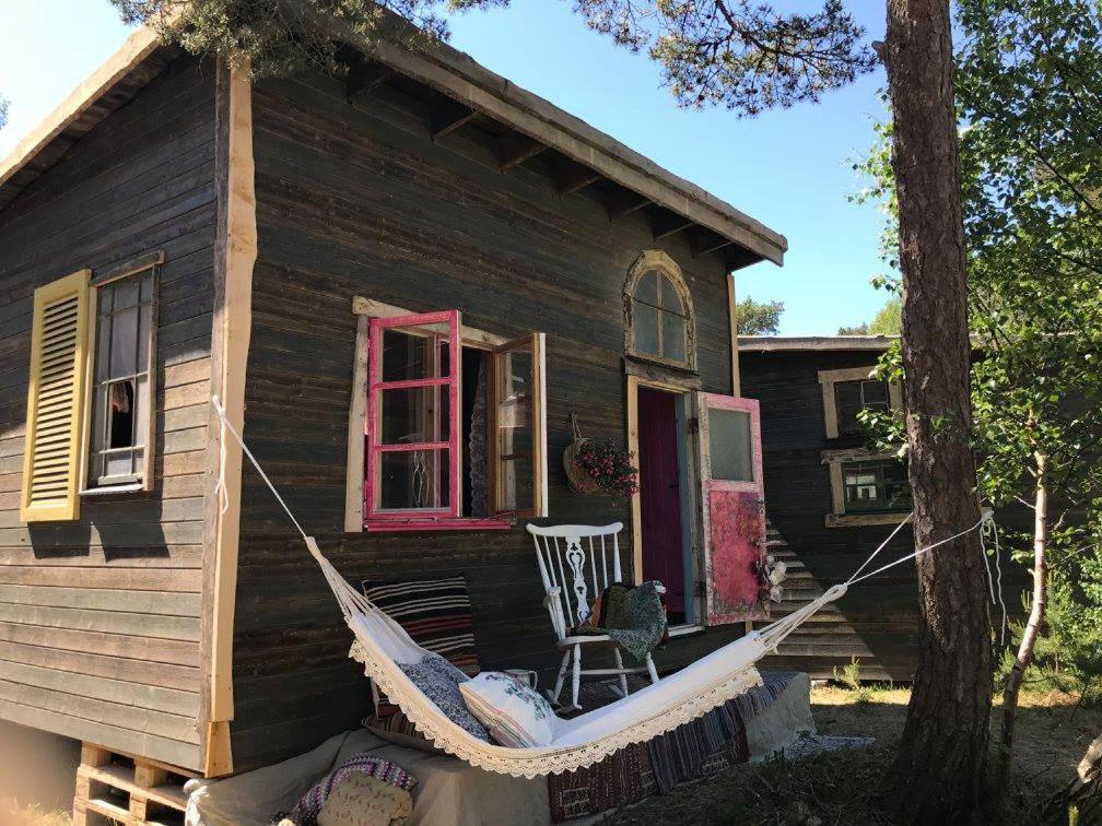 FidenäsFide Äventyrsby & Camping的吊床挂在房子外面,配有椅子