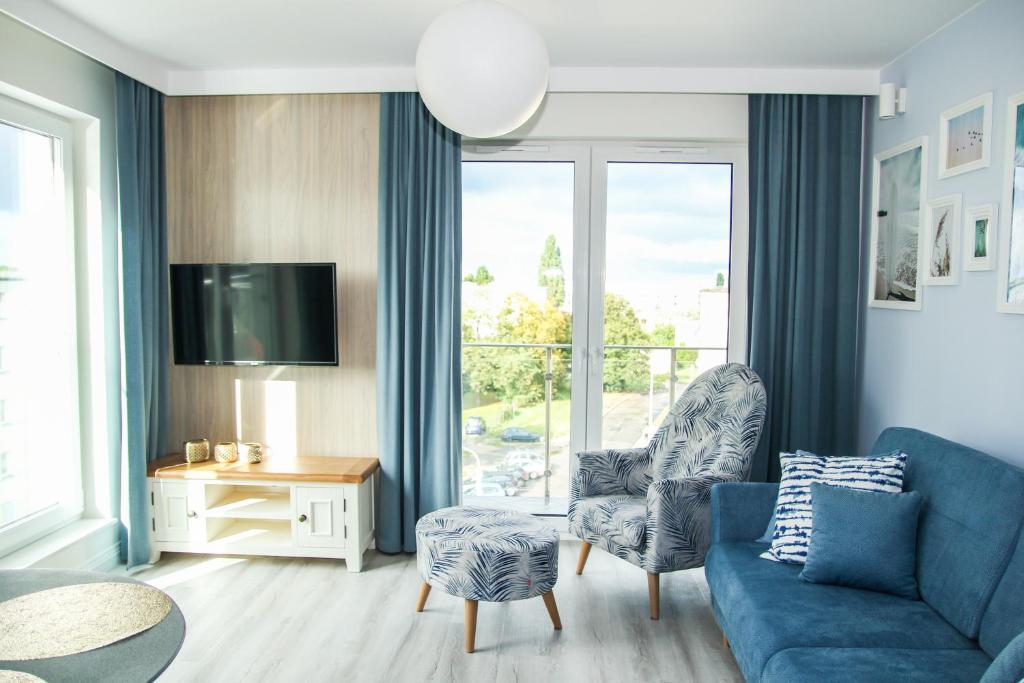 格但斯克Blueberry Apartment的客厅设有蓝色的沙发和大窗户