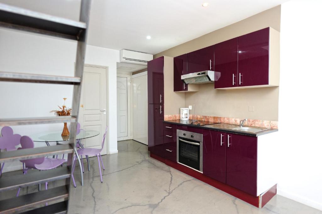 宗扎Appartement du Tourisme的厨房配有紫色橱柜和桌椅