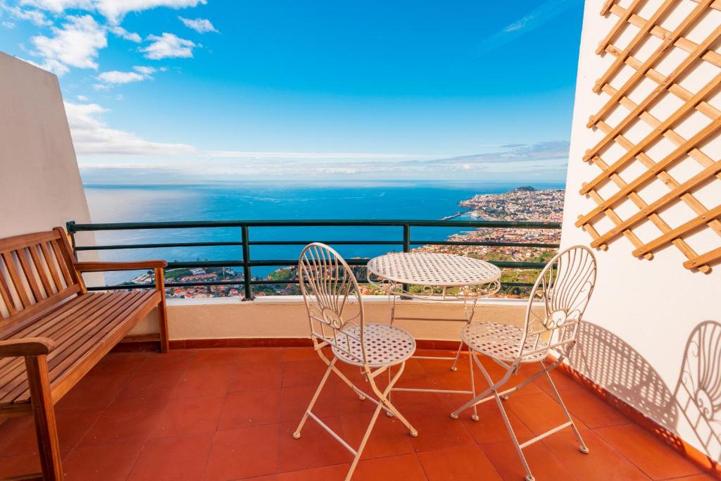 丰沙尔FLH Funchal Ocean View with Pool的阳台配有桌椅,享有海景。