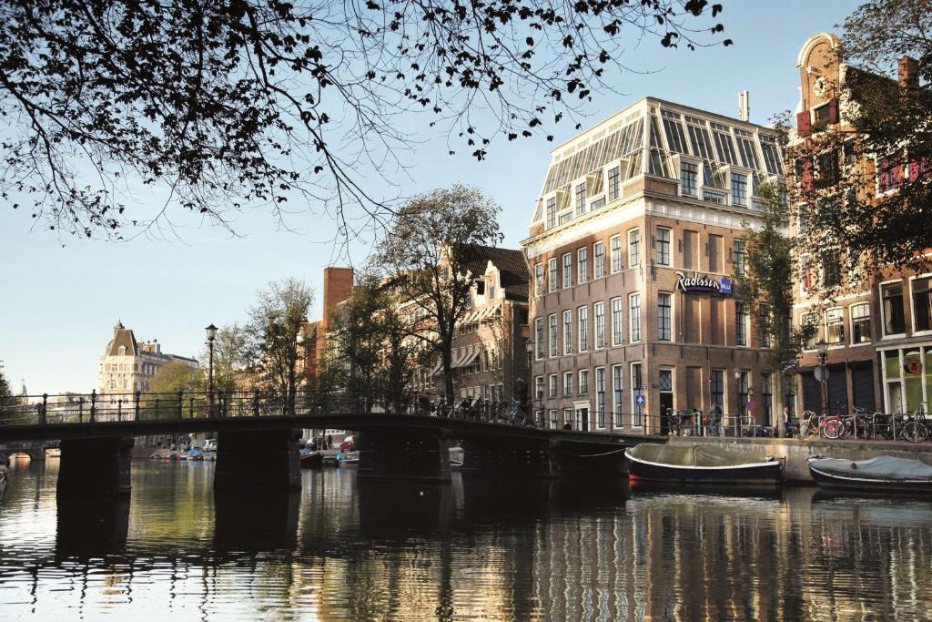 阿姆斯特丹Radisson Blu Hotel, Amsterdam City Center的一座建有建筑物的城市里河流上的桥梁