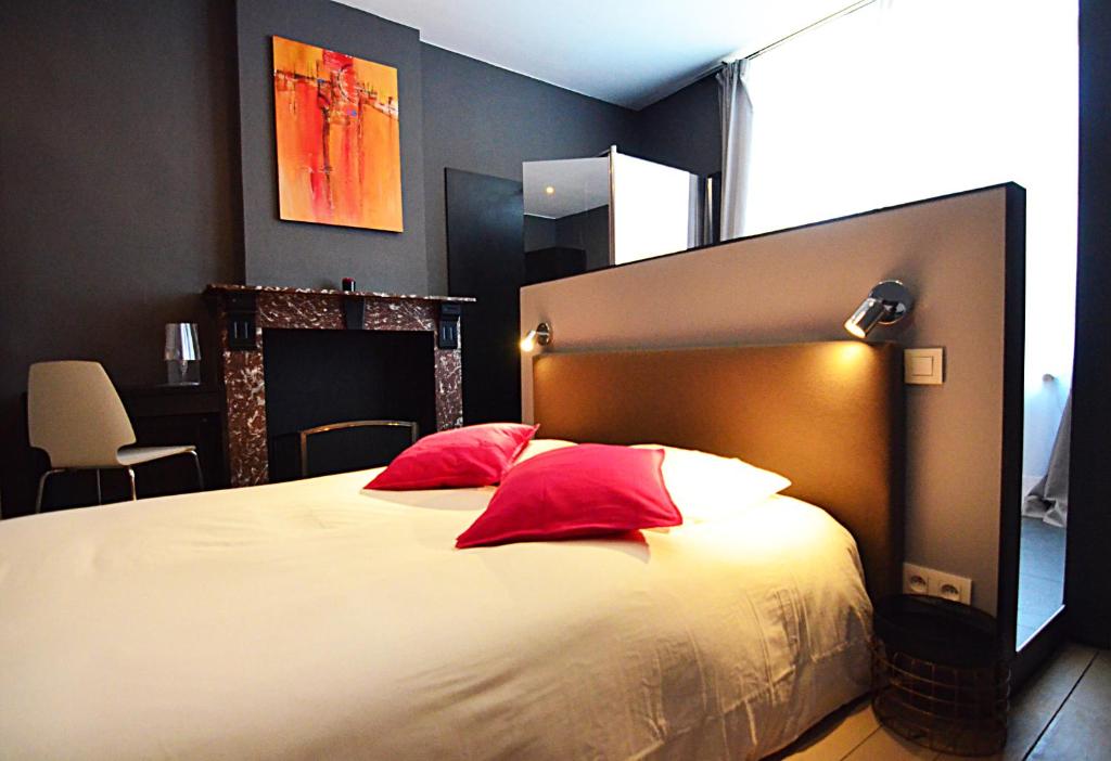 讷沙托La Citadine的一间卧室配有一张带红色枕头的大床