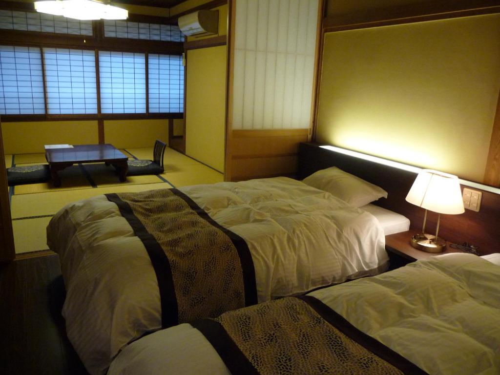 长野吉扎肯松屋旅馆的一间卧室配有两张床和一张带台灯的桌子