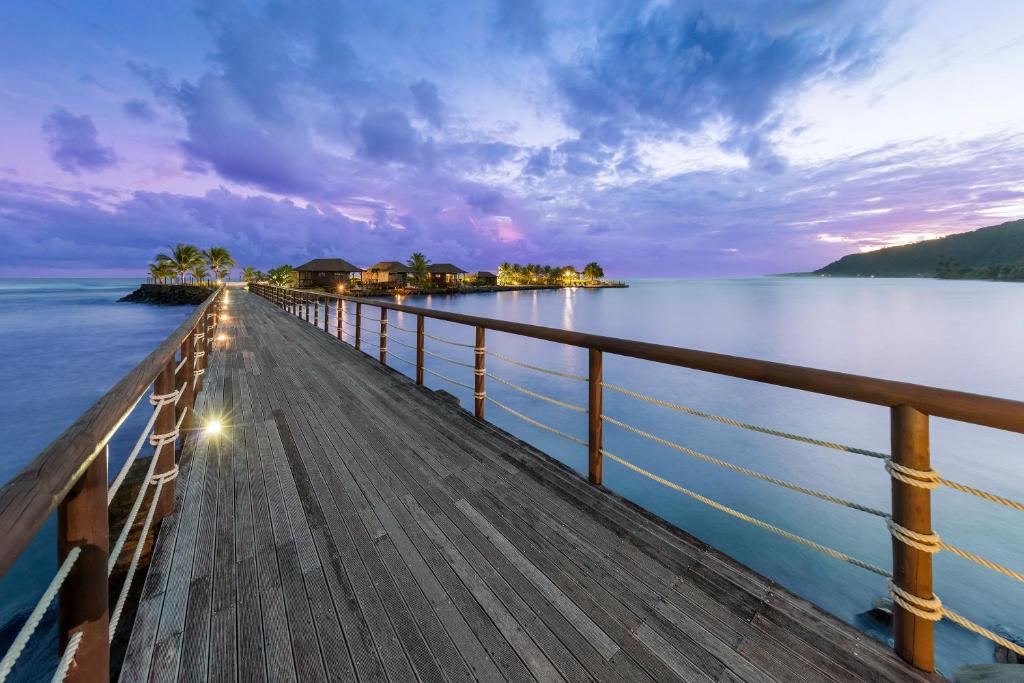 Lalomanu阿迦珊瑚礁度假村及Spa酒店的日落时分,一个木码头延伸到水中