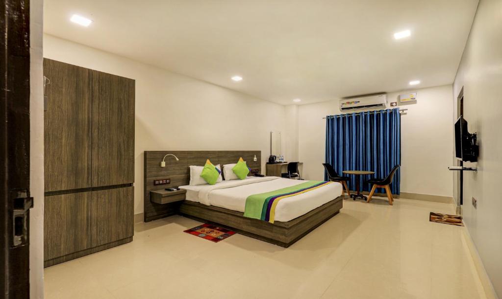 古瓦哈提Treebo Trend Arna Residency的一间卧室配有一张床、一张桌子和一把椅子
