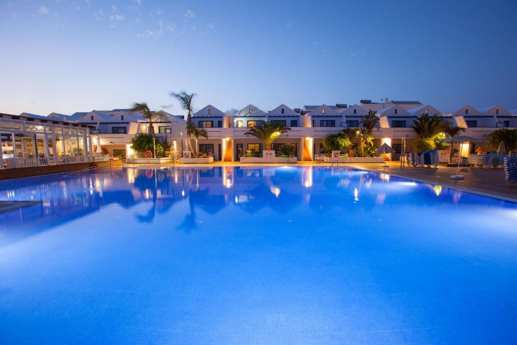 卡门港Grupotel Cinco Plazas的一座大型蓝色游泳池,其背景是房屋