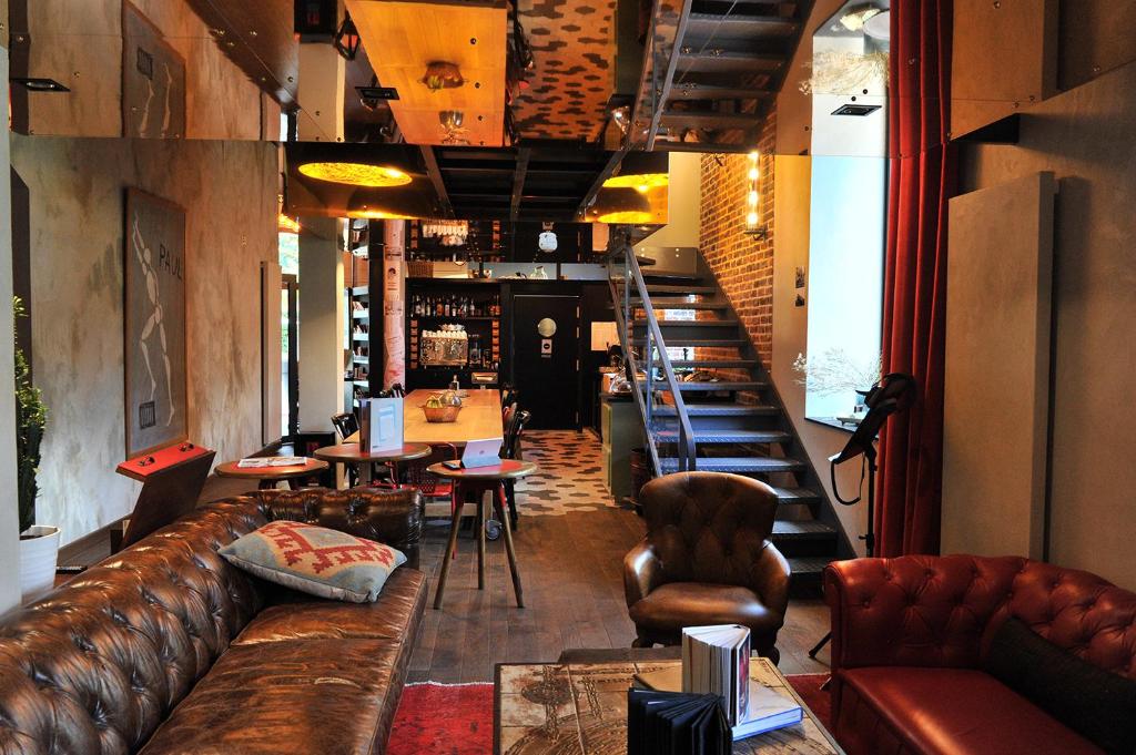 雷恩乐魔厅酒店的酒吧配有棕色皮沙发和椅子
