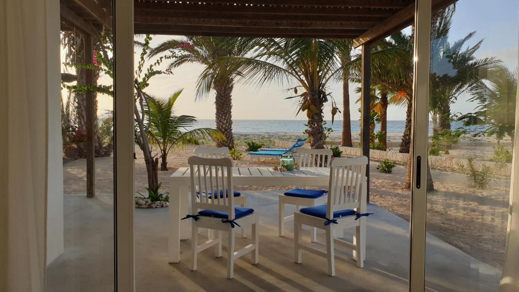 CabeçadasBeachhaus Praia de Chaves的海滩上带2把椅子和1张桌子的门廊