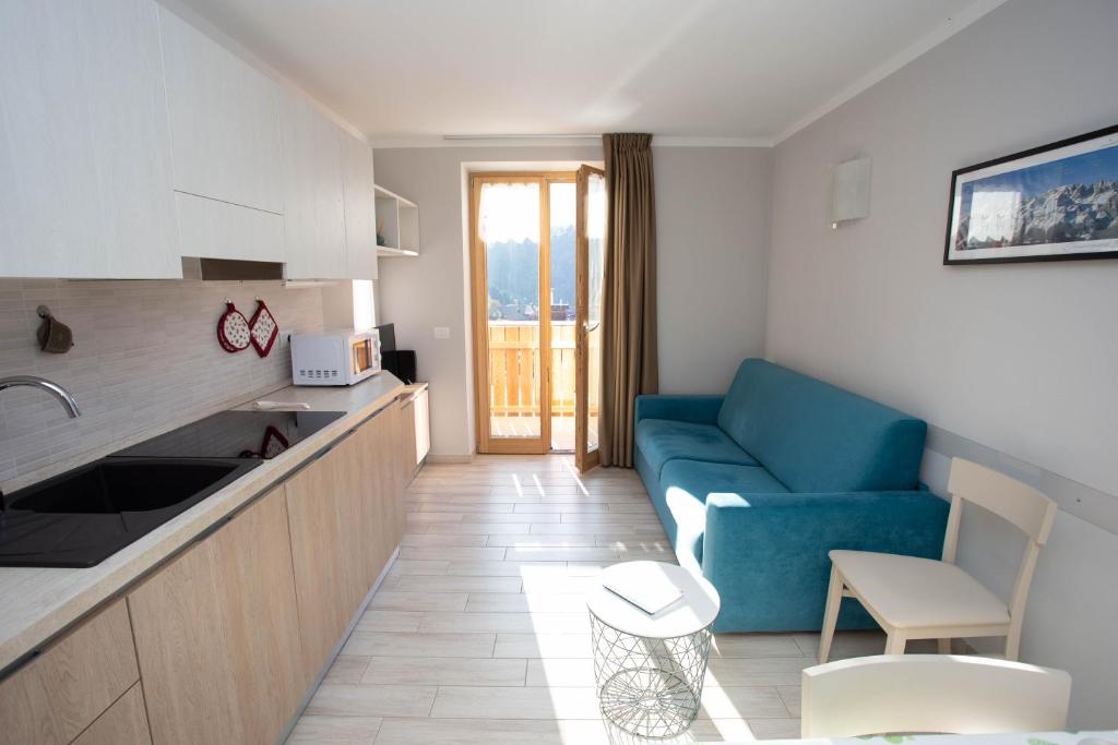 安达洛Perla delle Dolomiti的一间带蓝色沙发的客厅和一间厨房