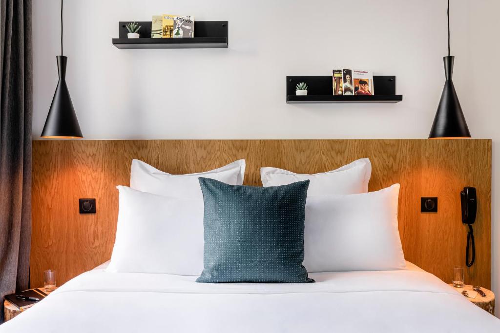 巴黎9Hotel Bastille-Lyon的一间卧室配有带白色床单和蓝色枕头的床。