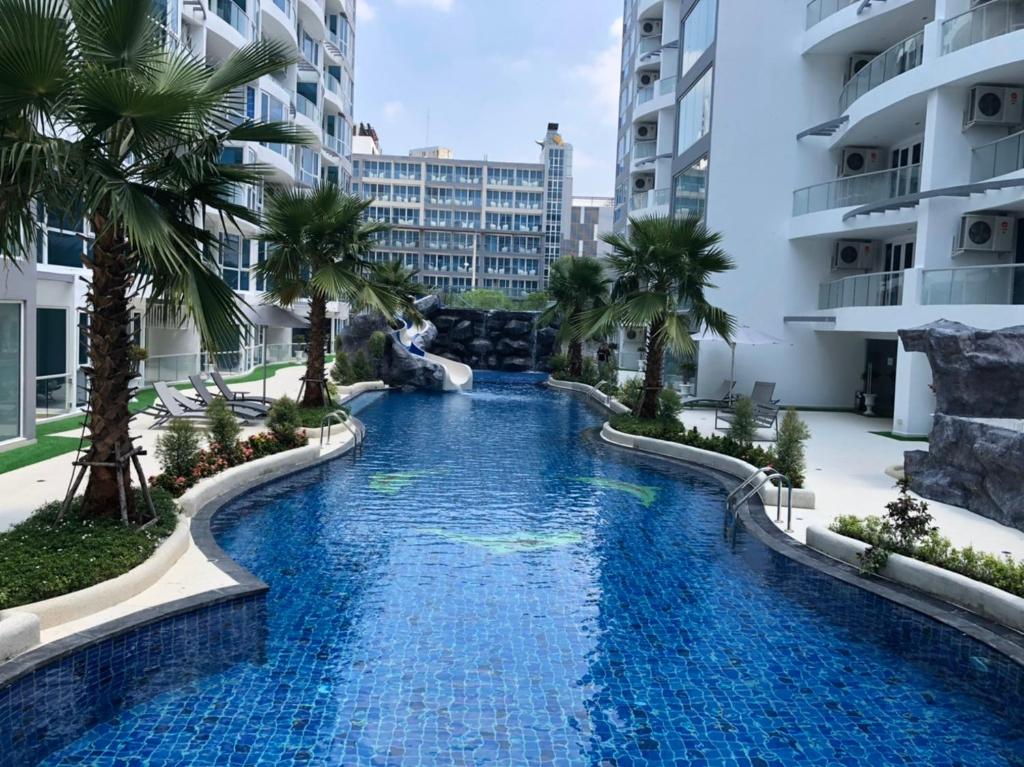 芭堤雅市中心Luxury Business Suits in Grand Avenue by Pattaya City Estates的棕榈树建筑中间的游泳池