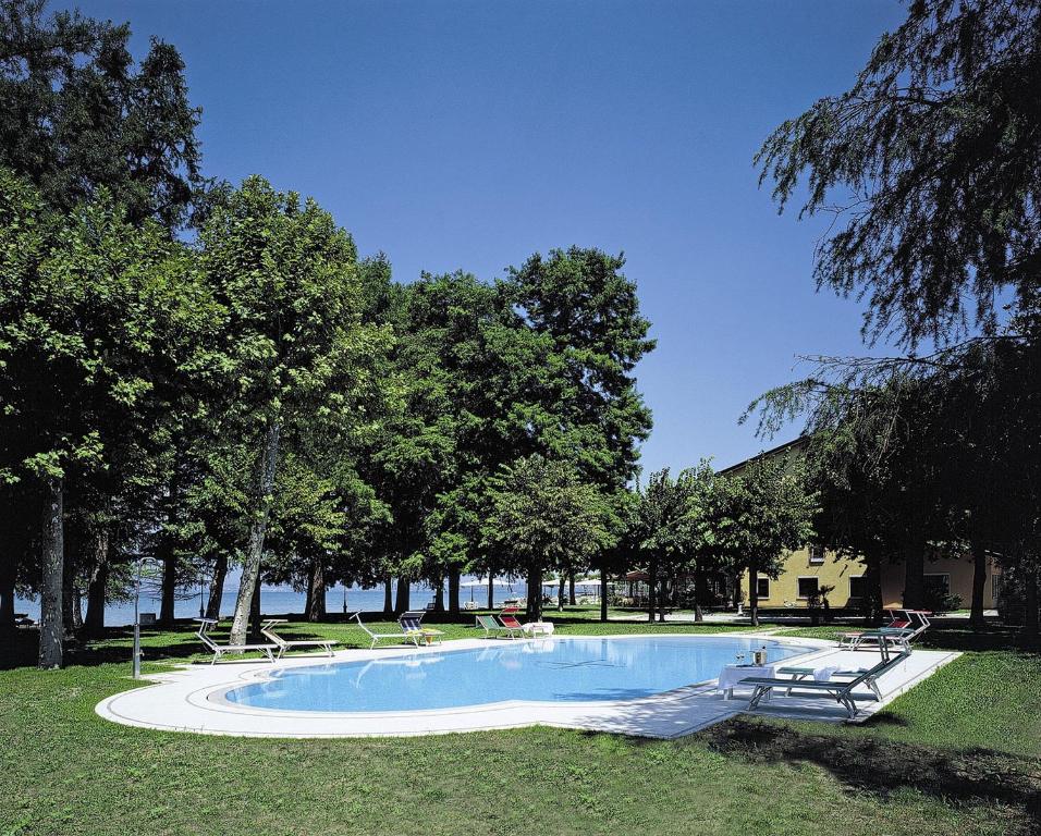 西尔米奥奈路加那帕可阿拉戈酒店的公园里的一个游泳池,有树和椅子